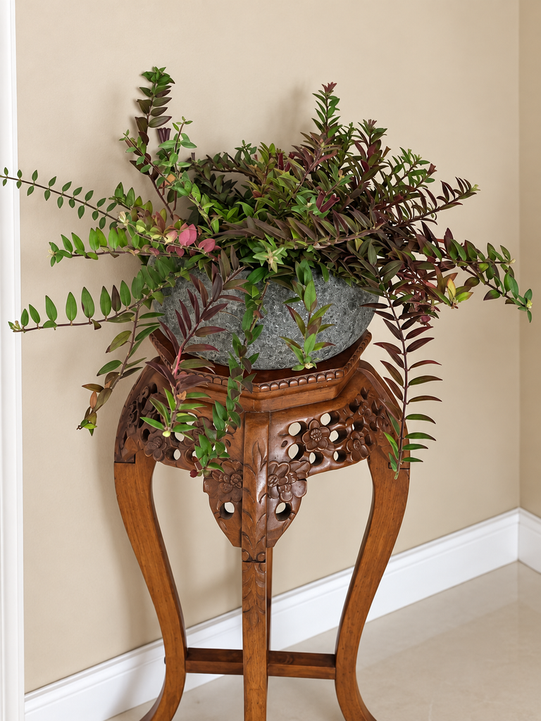 Folhagem ornamental em vaso sobre mesinha lateral de madeira